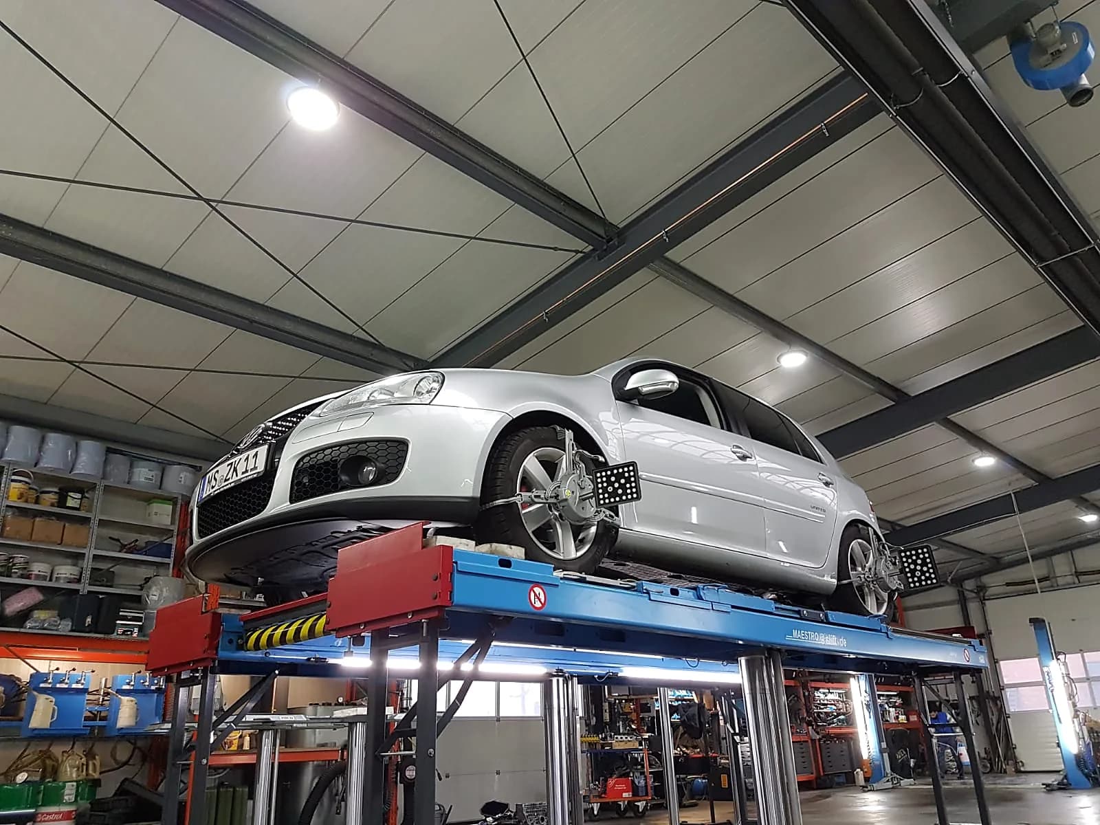 VW Golf GTI auf Achsmessbühne mit montierten Achsmesssensoren in der Werkstatt