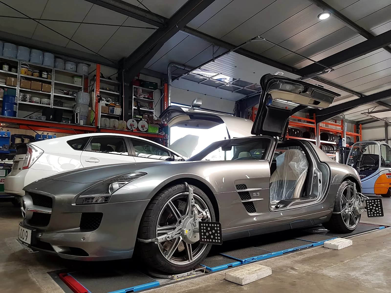 Mercedes SLS AMG mit geöffneten Flügeltüren auf Achsmesstand in der Werkstatt