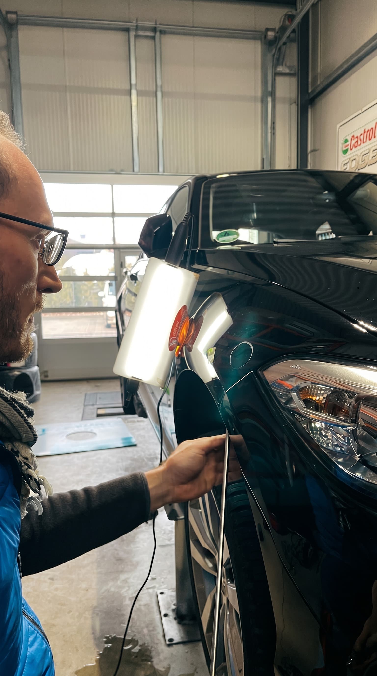 Lack-Inspektion an schwarzem Auto mit Lampe vor der Smart-Repair-Korrektur